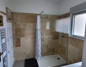 ein Bad mit einer Dusche und einer Glastür in der Unterkunft Chambre Chez Sandra et Fabien dans petite maison cœur village in Maubec