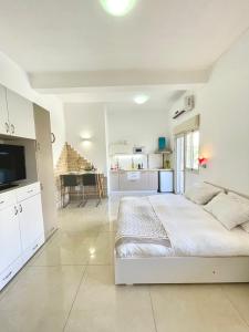 a white bedroom with a large bed and a kitchen at Bat Galim - by the sea in Haifa