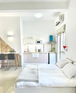 a white bedroom with a bed and a kitchen at Bat Galim - by the sea in Haifa