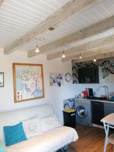 a living room with a white couch and a kitchen at Le Garni Vendémiaire in Vesoul