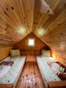 two beds in a log cabin with a window at Eko Katun Damjanovic - Bjelasica in Mojkovac