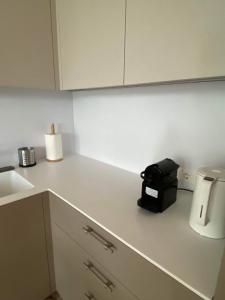 uma cozinha com uma bancada branca com um aparelho preto em Apartment-Pine Forest Birštonas em Birstonas