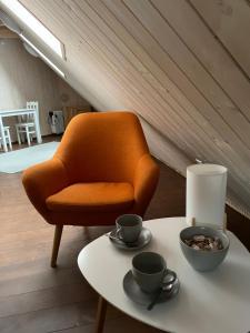 una silla naranja sentada junto a una mesa con tazas. en Toila Sadamakapteni tuba, en Toila