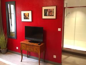 Habitación con pared roja y mesa con TV. en L'Estaminet, en Mazille