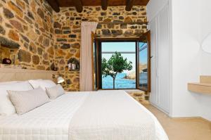 sypialnia z dużym łóżkiem w kamiennej ścianie w obiekcie Palio Damnoni Seafront House w mieście Damnoni