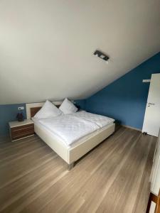 a bedroom with a white bed and a blue wall at Ferienwohnung MaRe in Oberteuringen