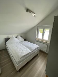 a bedroom with a white bed and a window at Ferienwohnung MaRe in Oberteuringen