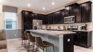 a kitchen with wooden cabinets and a large island with bar stools at 8972 Amelia Downs in Orlando