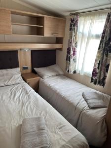 two beds in a small room with a window at Sea Breeze Cabin in Poole
