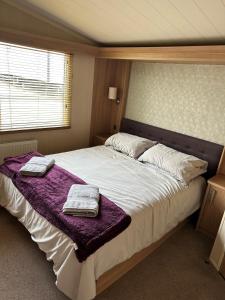 a bedroom with a large bed with two towels on it at Sea Breeze Cabin in Poole