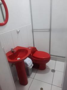 uma casa de banho com um WC vermelho e um lavatório vermelho. em Casa Grande em Iquitos