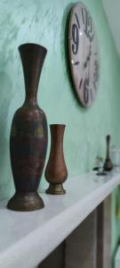 três vasos sentados numa prateleira com um relógio em Lastva star em Donja Lastva