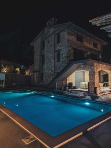 a swimming pool in front of a house at night at Three Dots Boutique Suites in Soúlion
