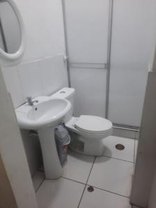 a white bathroom with a toilet and a sink at Casa Grande in Iquitos