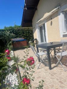 un patio con mesa, sillas y flores en Maison Time Break Jacuzzi - 4 étoiles en Thonon-les-Bains