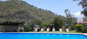 una piscina con sillas y una montaña en el fondo en Hotel el Arco en Valle de Bravo