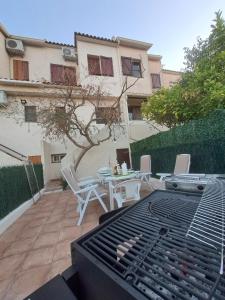 a patio with a grill and a table and chairs at Casa apareada cerca de la playa in Torredembarra