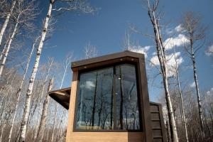 a glass house in the woods with trees in the background at Refuge Bay's Aqua Tiny Home - Luxury Off Grid Escape 