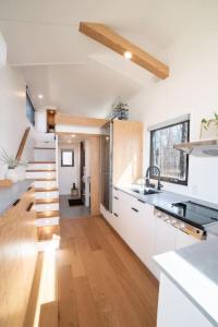 een moderne keuken met witte kasten en een trap bij Refuge Bay's Aqua Tiny Home - Luxury Off Grid Escape 