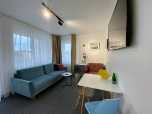 ein Wohnzimmer mit einem blauen Sofa und einem Tisch in der Unterkunft Apartament 215 Planeta 2-pokojowy z balkonem in Mielno