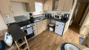 a small kitchen with a stove and a sink at Cozy Private Static Caravan at Llyons Robin Hood - Silver Birch Way 11 in Rhyl