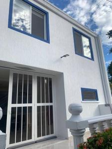 une maison blanche avec des fenêtres bleues et une porte dans l'établissement Amazing Home Ricaurte-Casa verano piscina-Aire acondicionado, à Ricaurte