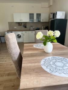 a wooden table with two chairs and a vase of flowers at Ferienwohnung Villa Einetal in Aschersleben