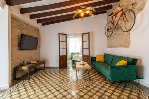 een woonkamer met een groene bank en een fiets aan de muur bij Apartamento Boutique Kala Ático in Jerez de la Frontera