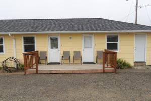 a yellow house with chairs on a wooden porch at The Lowtide Motel in Copalis Beach