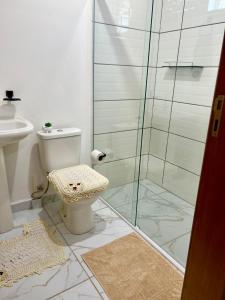 a bathroom with a toilet and a glass shower at Suítes Recanto Monte trigo in São Francisco do Sul