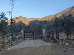 a wooden gate with a fence in front of a mountain at Cabañas Ocoa in Hijuelas