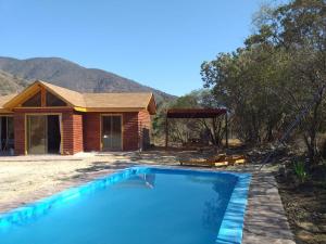 a house with a swimming pool in front of a house at Cabañas Ocoa in Hijuelas