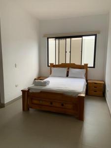 1 dormitorio con cama de madera y ventana en Hotel Hacienda Guane Urbano en Oiba