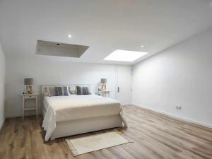 biała sypialnia z dużym łóżkiem i drewnianą podłogą w obiekcie Mazi Apartments Cuba w mieście Mataró