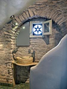 a stone bathroom with a sink and a window at Sea View Exclusive Studios - Tinos in Agios Ioannis Tinos