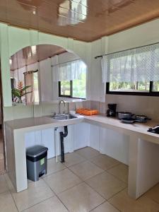 una cocina con encimeras blancas, fregadero y ventanas en Kiskadee House, en Rancho Quemado