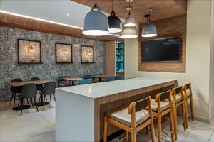 a bar in a restaurant with chairs and a flat screen tv at Fairfield by Marriott San Jose Airport Alajuela in Alajuela City