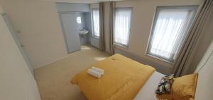 Habitación pequeña con cama amarilla y lavabo. en Sunset de Luz, en Nijmegen