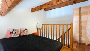 a bedroom with a black bed and a staircase at Maison de village avec garage in Aigues-Mortes
