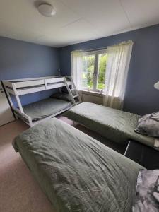 a bedroom with three bunk beds and a window at Stugby Marieke - Skärvången in Föllinge