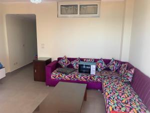 sala de estar con sofá púrpura y TV. en PORTO MARINA North Coast -الساحل الشمالي بورتو مارينا العلمين en El Alamein