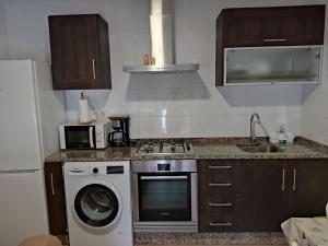a kitchen with a stove and a washing machine at CA Apartamentos Pampin Ponte do Porto in Ponte Do Porto