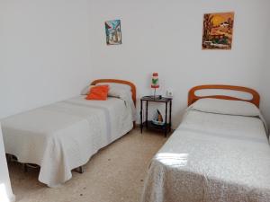 Dos camas en una habitación con sábanas blancas. en La Casa de la Abuela Jesús, en Sanlúcar de Barrameda