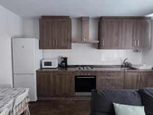 uma cozinha com armários de madeira e um frigorífico branco em RO Apartamentos Pampin Ponte Do Porto em Ponte Do Porto