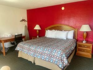 Habitación de hotel con cama y pared roja en Rodeway Inn, en Flora