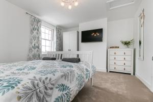 a white bedroom with a bed and a dresser at Mill Dam Lake House in Saint Osyth