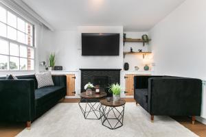 uma sala de estar com dois sofás pretos e uma lareira em Mill Dam Lake House em Saint Osyth