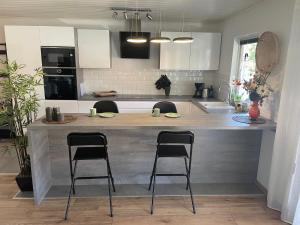 a kitchen with a large counter with three bar stools at Sentralt beliggende moderne leilighet in Mosjøen +3 photos