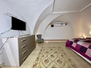 um quarto com uma cama e uma cómoda com uma televisão em Living Dalia em Carovigno