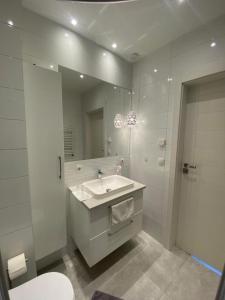 a white bathroom with a sink and a mirror at Rhein Appartements in Rheinhausen